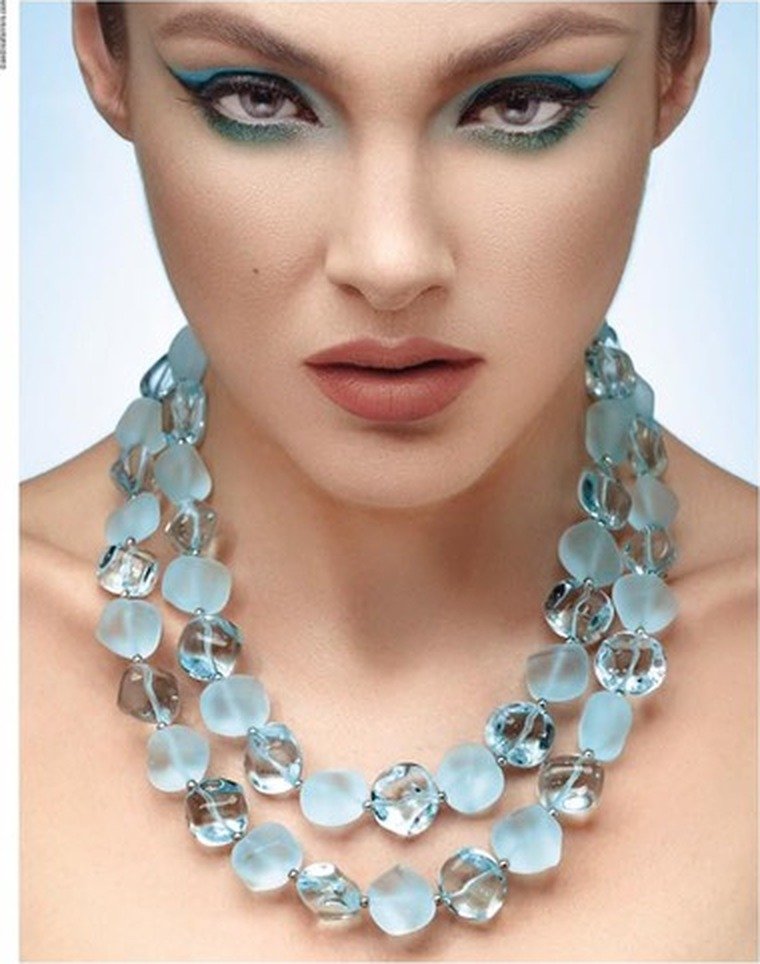 Model wearing a triple-strand necklace of aqua Murano glass beads